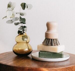 soaps with shaving brush near vase on wooden table